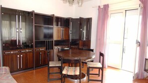 Un comedor con una mesa redonda y sillas, un aparador con puertas de vidrio y una puerta con cortina.