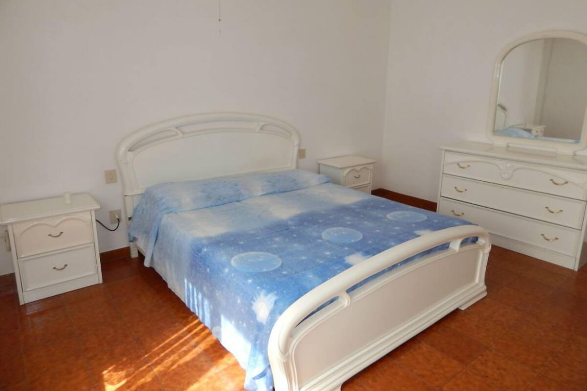 A bedroom with a bed, a nightstand, a dresser, and a mirror.
