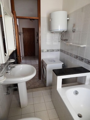 Un baño con lavamanos, lavadora y bañera.