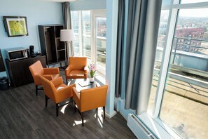 A hotel room with a large window, a desk, a chair, a lamp, and a picture on the wall. - The Hague Teleport Hotel - Free Parking (The Hague)