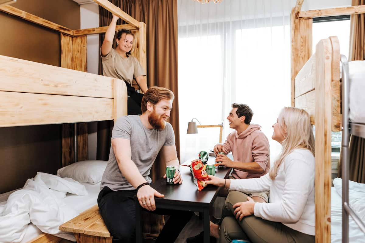 Une pièce avec des lits superposés, une table en bois avec des collations et une fenêtre avec des rideaux.