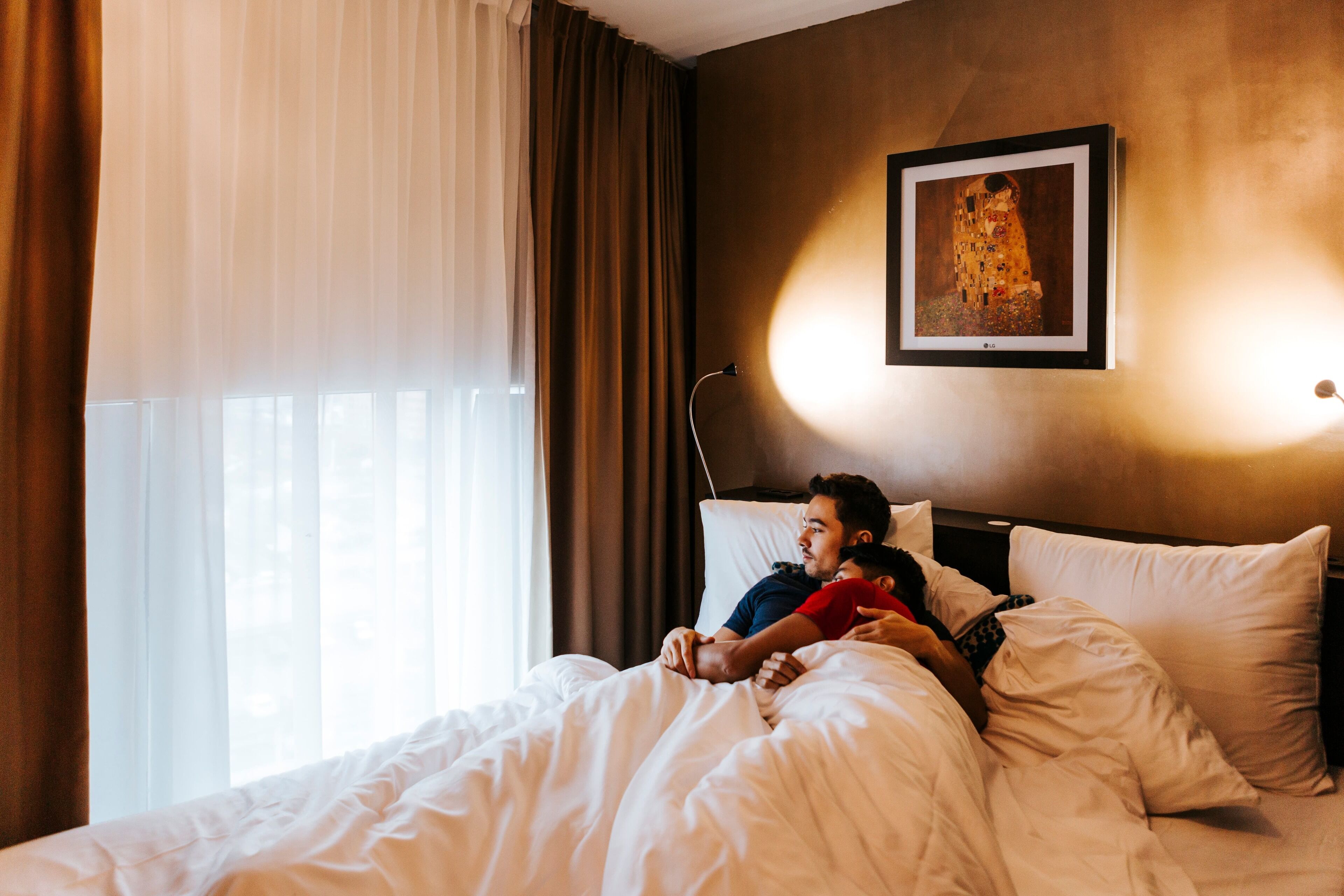 A hotel room with a bed, a nightstand, a lamp, and a painting on the wall.