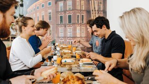 Een groep mensen zit aan tafel en geniet van ontbijt en drankjes.