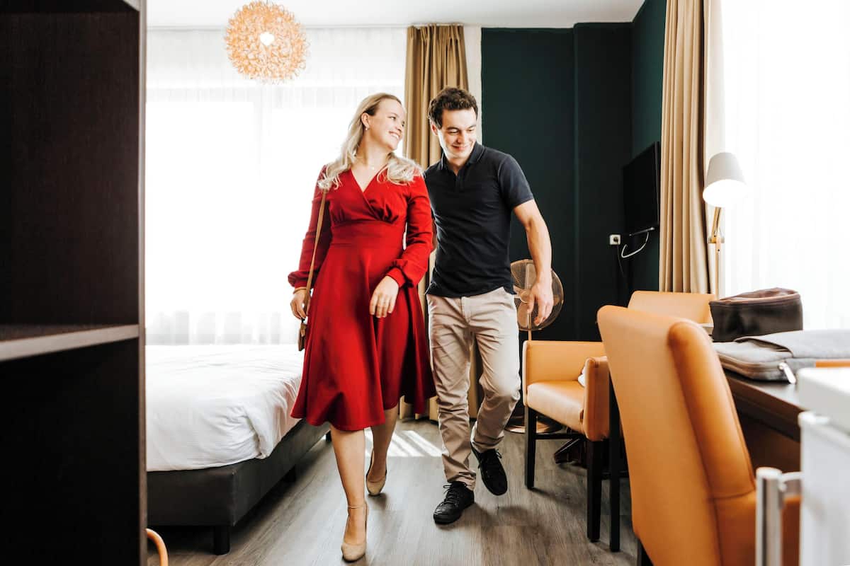 Une chambre d’hôtel avec un lit, un bureau et une chaise.