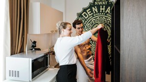 Een hotelkamer met een magnetron, een handdoekhouder en een grote spiegel.