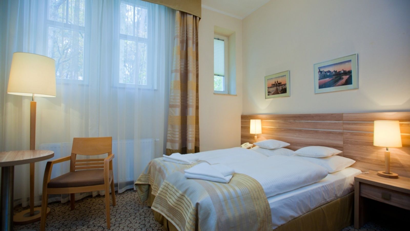 Una camera d'albergo con un letto, una sedia, un tavolo e due lampade.