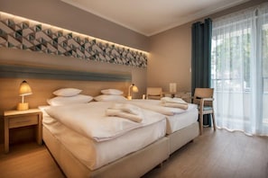 Habitación de hotel con una cama grande, lámparas de noche, una silla y vistas al exterior.
