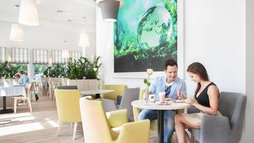 Uma sala de jantar moderna com cadeiras amarelas, mesas redondas e iluminação pendente.