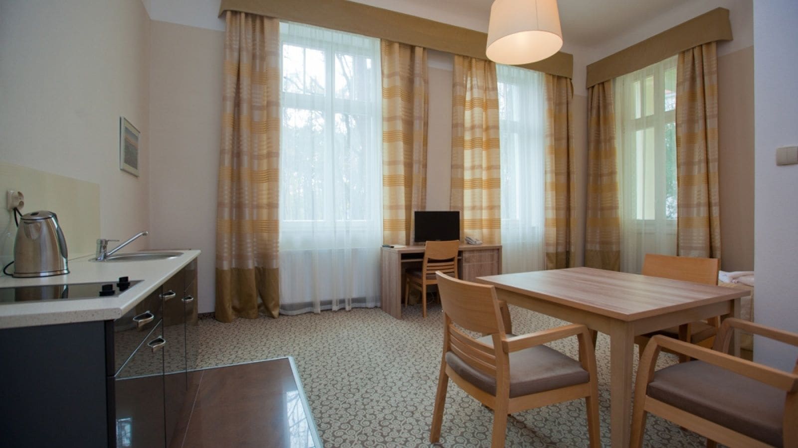 Et kompakt hotelværelse med tekøkken, spiseplads og fjernsyn.
