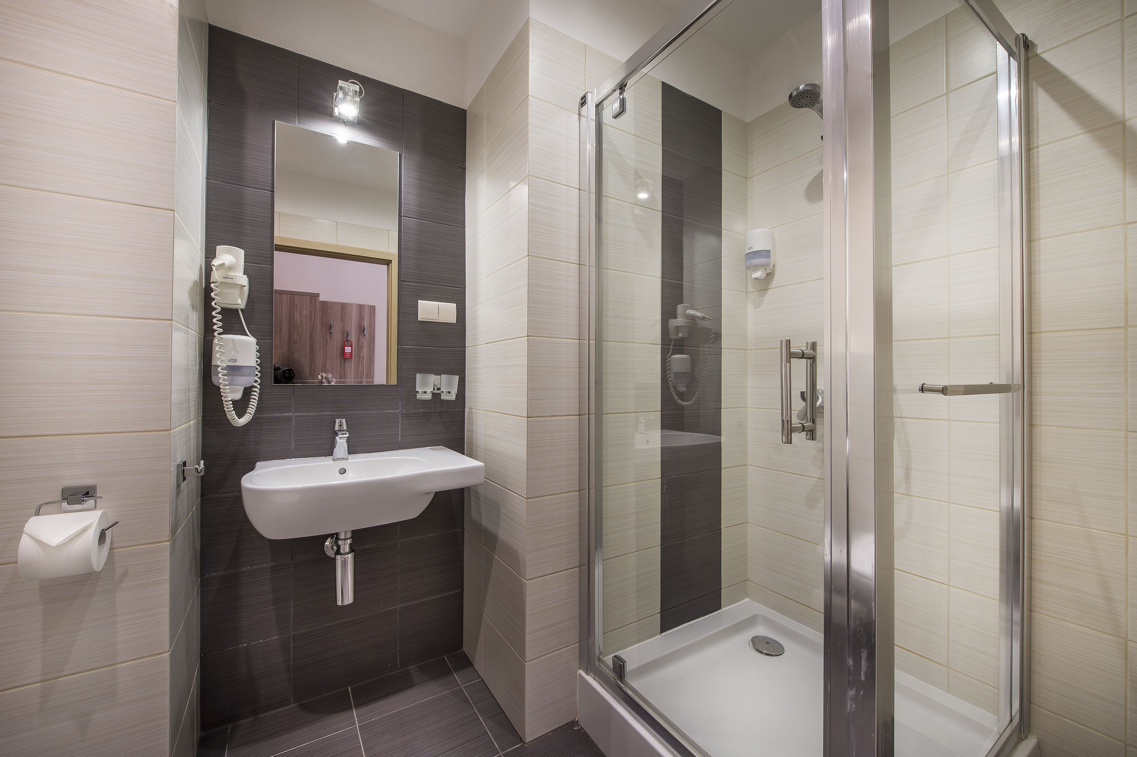 Un baño moderno con ducha envuelta en vidrio, un lavamanos con espejo y un inodoro.