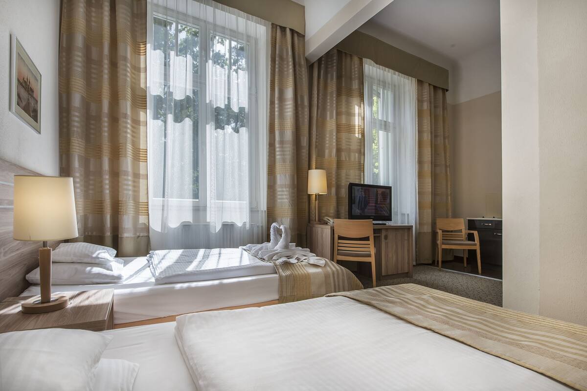 Ett hotellrum med två sängar, ett skrivbord, en tv och en stol.