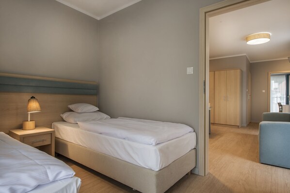 Una habitación de hotel con cama, mesita de noche, lámpara y vistas al pasillo.