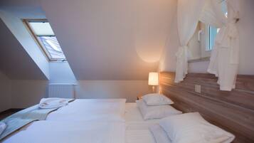 Un dormitorio con dos camas, tragaluz, lámpara de noche y cabecera de madera.