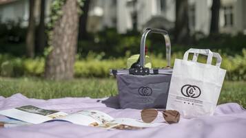 Une nappe est étalée, et on y a disposé un sac, des lunettes de soleil et une brochure, pour un pique-nique improvisé.