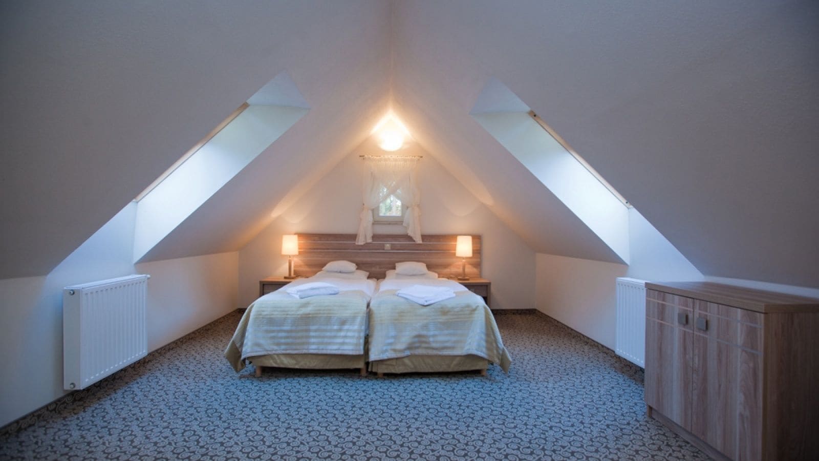 Ein Schlafzimmer mit zwei Betten, einem Fenster und einer Heizung.