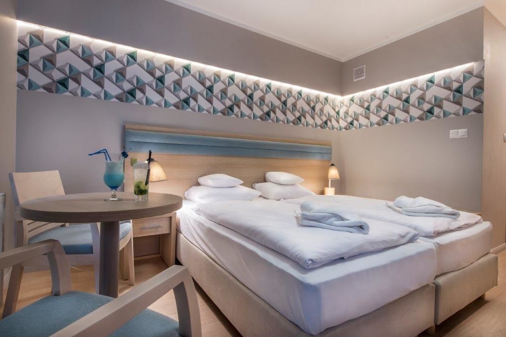 Une chambre d’hôtel avec un lit, des tables de chevet, une table ronde et une chaise.
