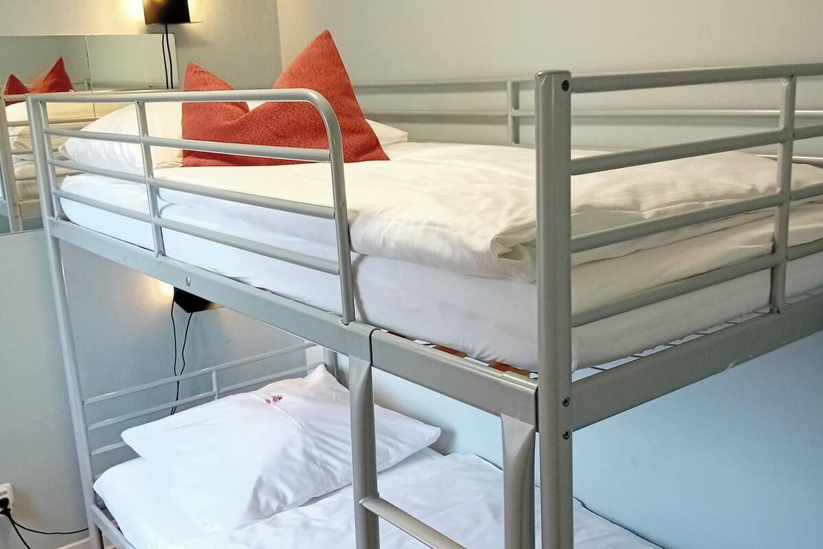 A bunk bed room with a light blue wall and a single bedside lamp.