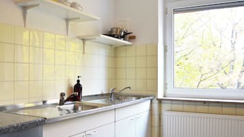 A kitchen with white cabinets, a stainless steel sink, and a window with a view of trees.