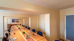Un salón de conferencias con una larga mesa, sillas y una pizarra.