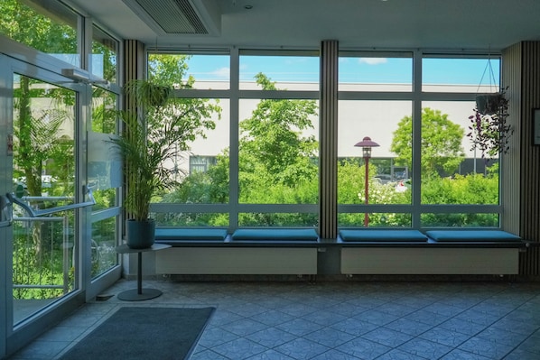 A room with large windows, a potted plant, and a bench. - JUGENDGASTEHAUS DRESDEN - Hostel (Dresden)
