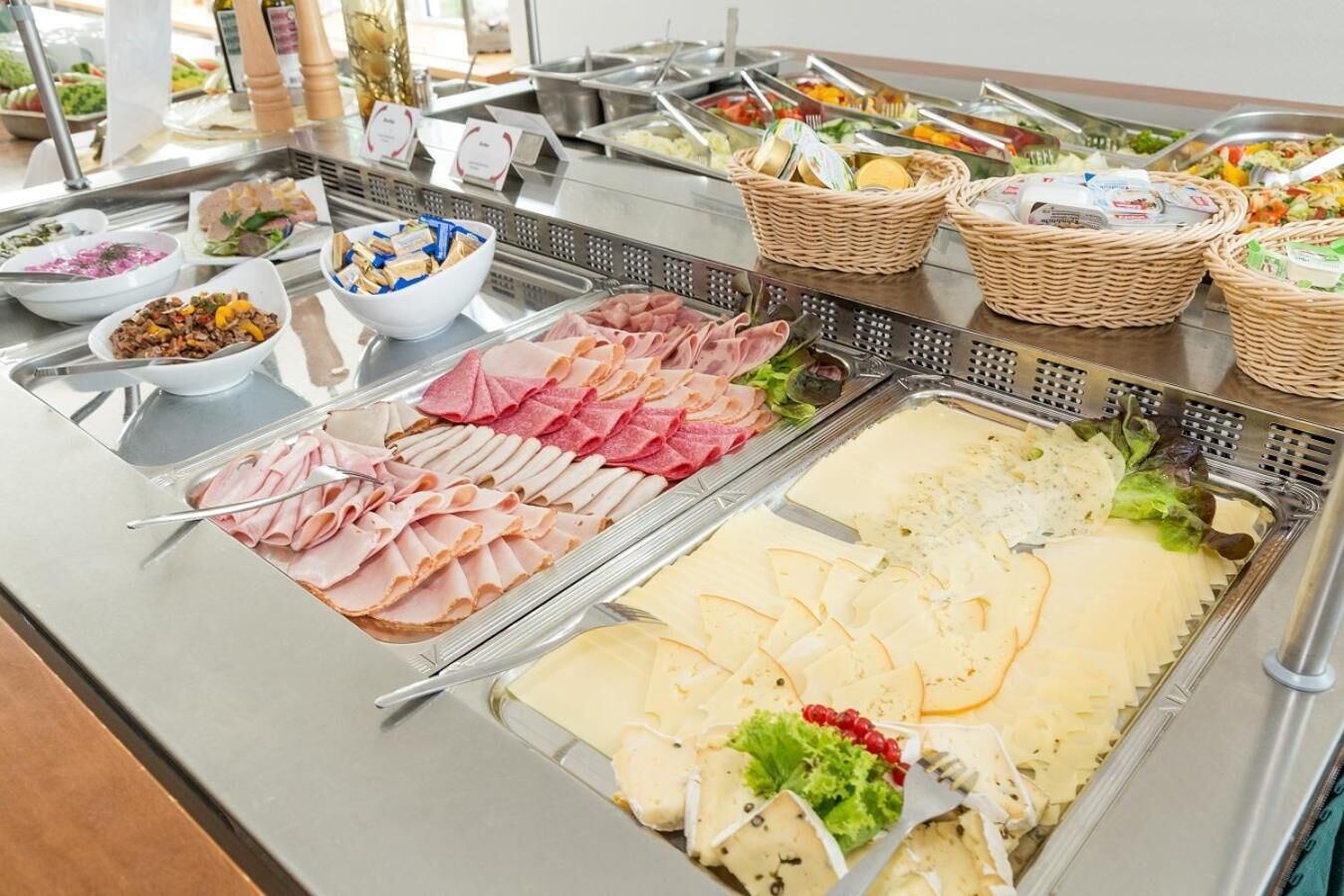 Een buffet met diverse soorten eten, waaronder vlees, kazen en salades.