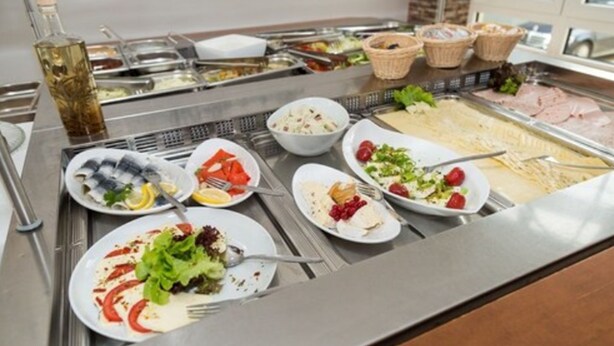 Un bufé con diversas opciones de comida, incluyendo ensaladas, frutas y carnes.