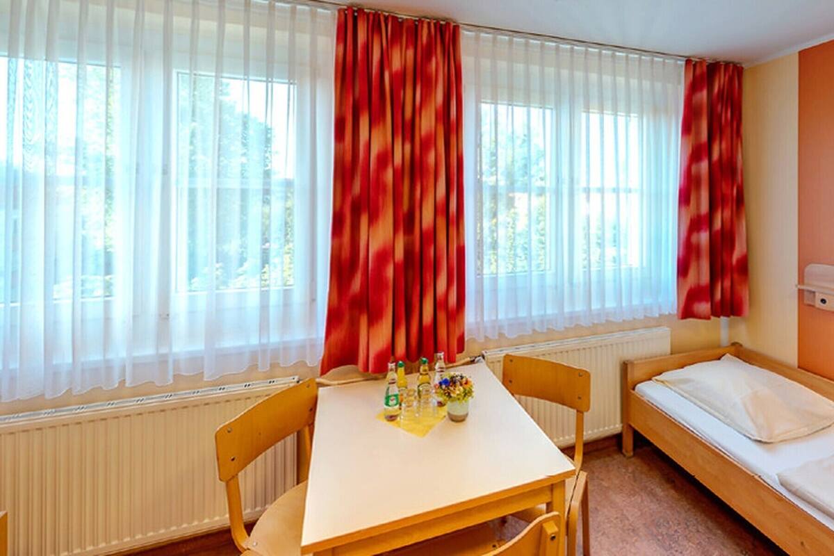 A small, single-room accommodation with a bed, a table, and a chair.