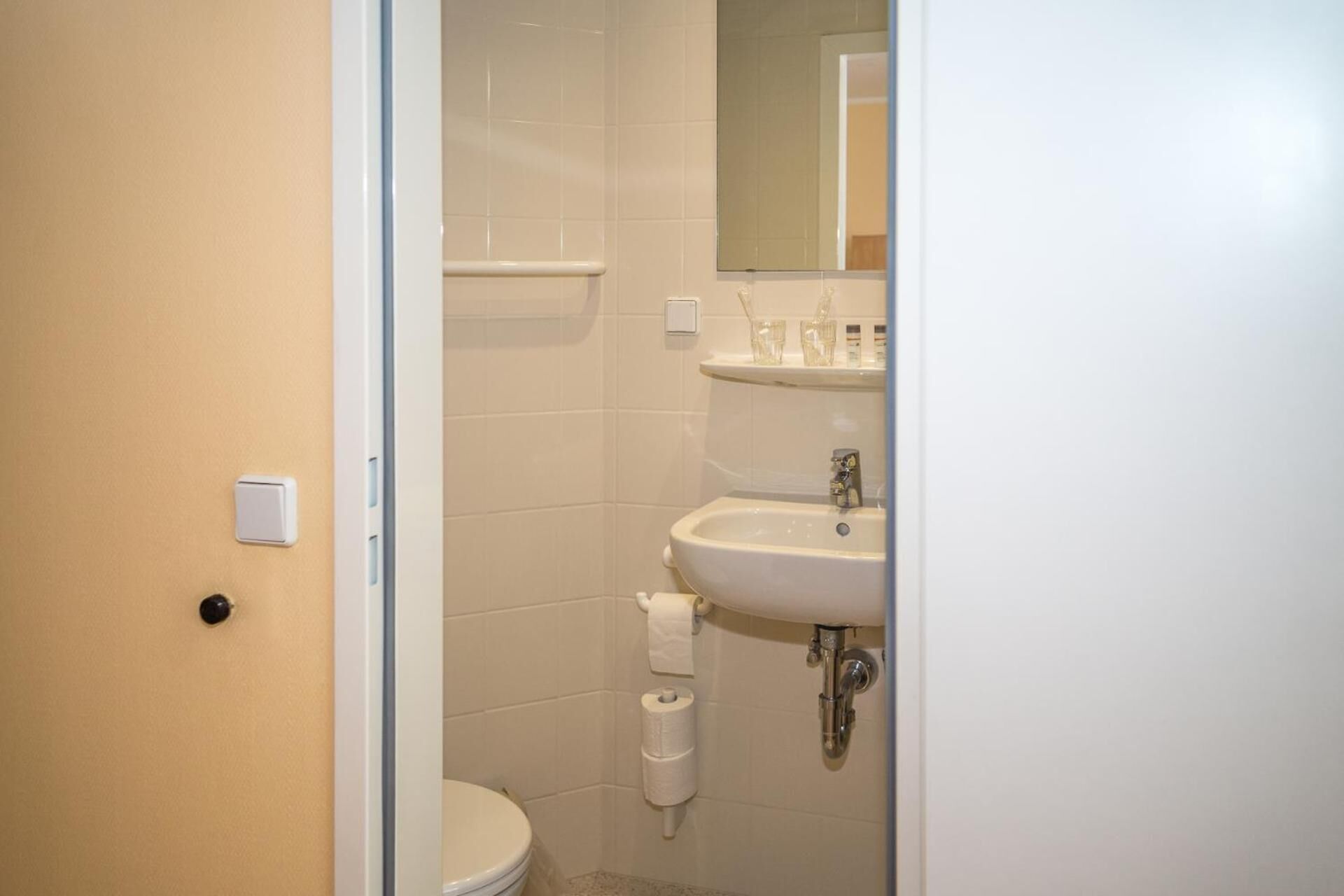 Ein kleines, sauberes Badezimmer mit Toilette, Waschbecken und Spiegel.