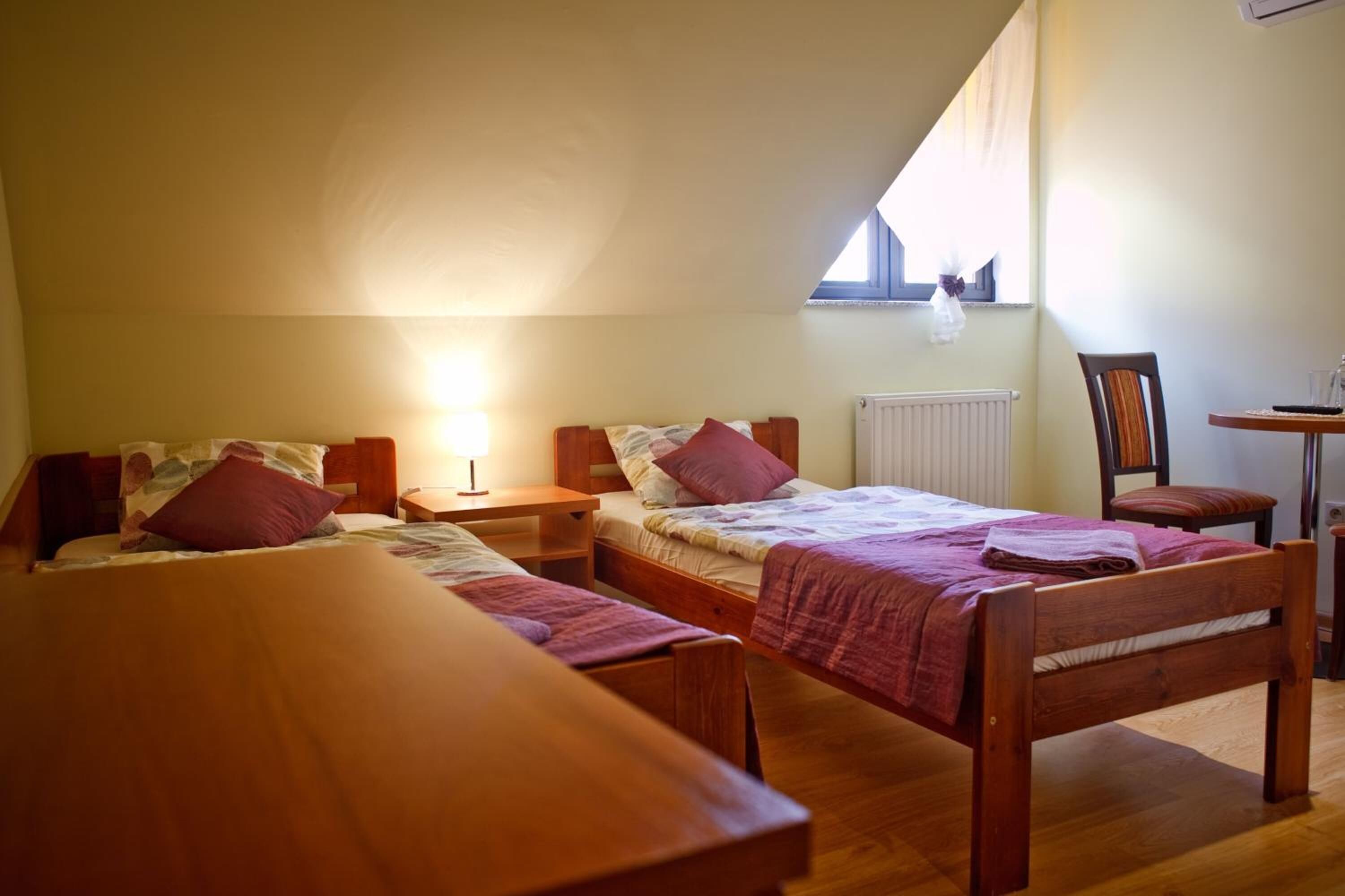 Ein Schlafsaalzimmer mit zwei Einzelbetten, einem Holztisch, einem Stuhl und einer Heizung.