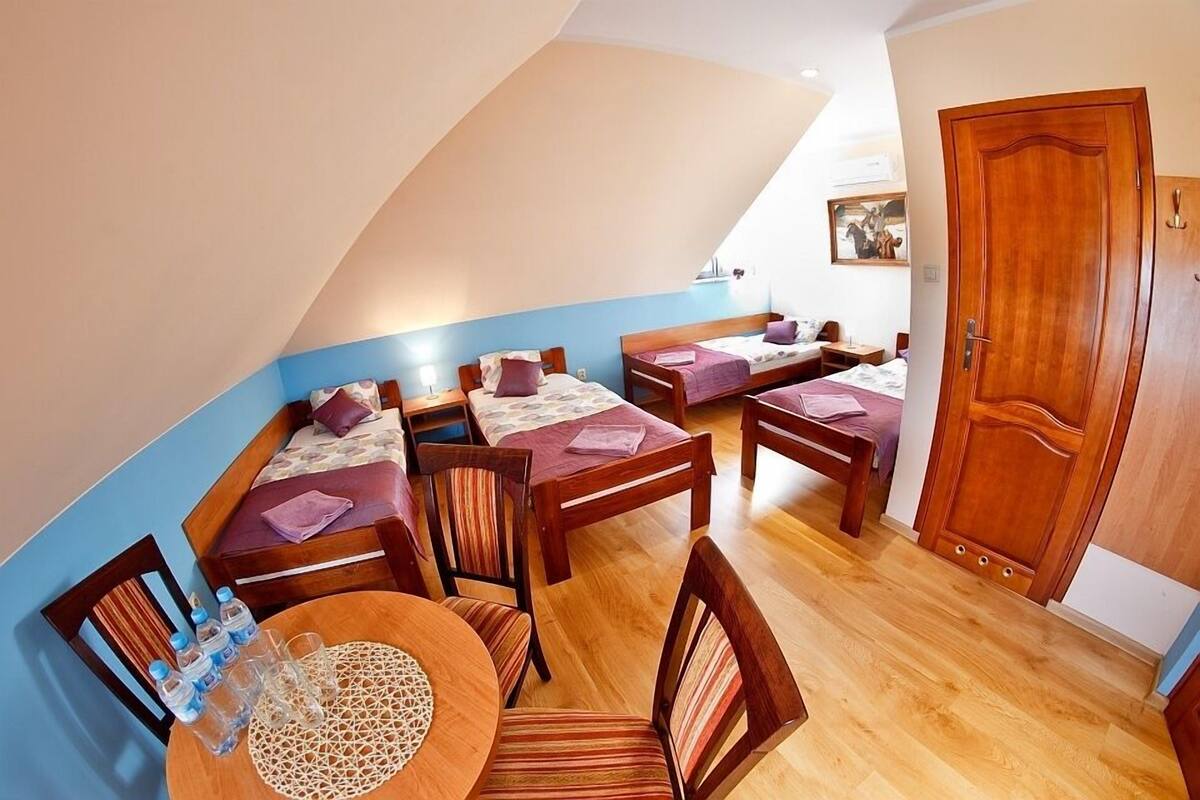 Un dormitorio con dos camas individuales, una puerta de madera y una mesa de comedor con sillas.