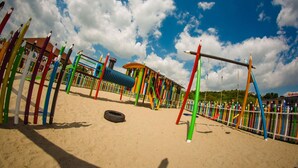 A playground with colorful equipment and a sandy ground.