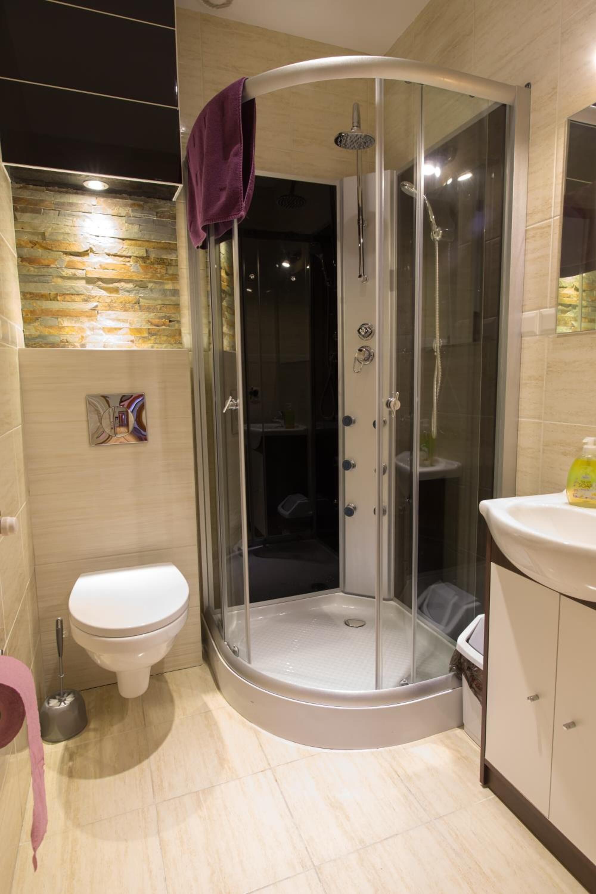 A modern bathroom with a glass-enclosed shower, a toilet, and a sink.