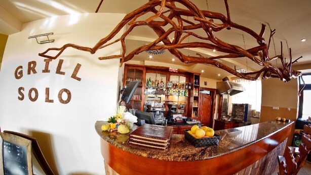 A restaurant counter with a rustic design, a chalkboard menu, and a variety of fruits and condiments.