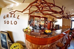 Un taulell de restaurant amb un disseny rústic, un menú escrit a la pissarra i una varietat de fruites i condiments.