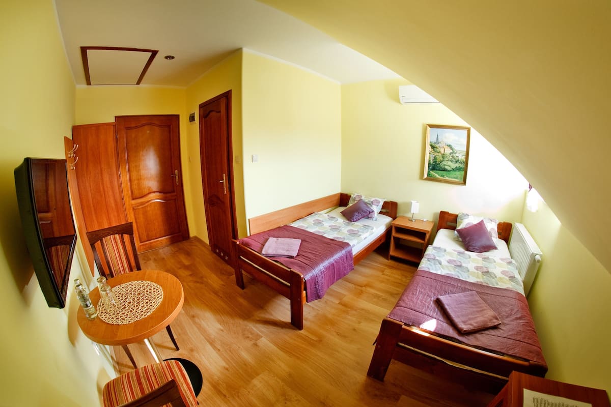 Una habitación con dos camas, una mesa de madera y una silla.