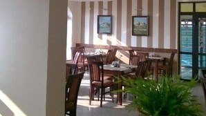 A restaurant with striped walls, wooden furniture, and a large plant in the foreground.