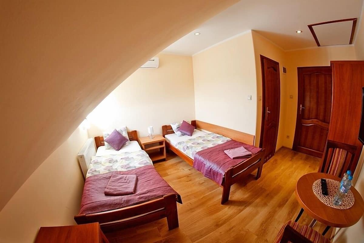 Un dormitorio con dos camas individuales, muebles de madera, una mesita y una puerta.