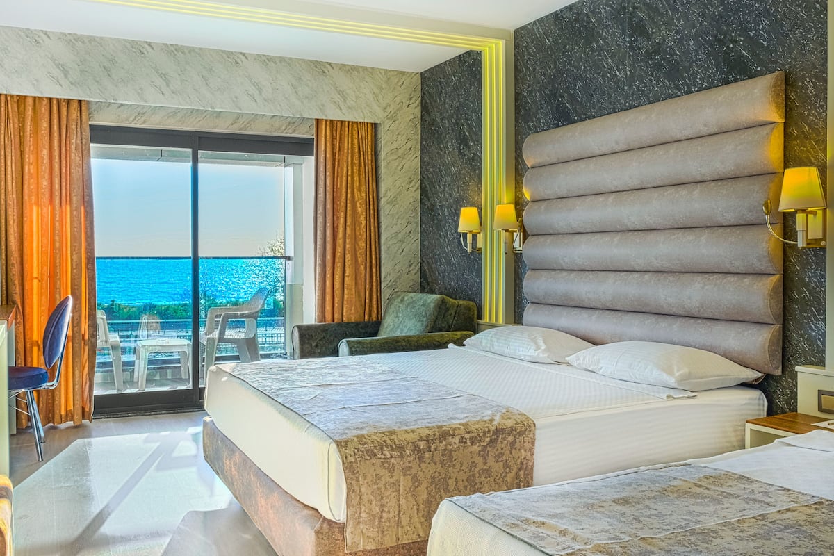 A hotel room with a large bed, a desk, and a view of the sea.