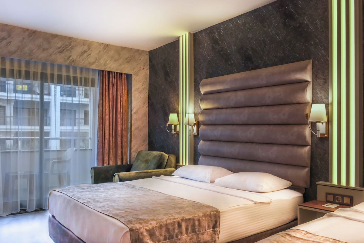 A modern hotel room with a large bed, a seating area, and a view of the outside.
