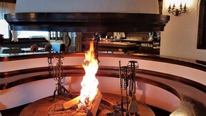 A stone fire pit with a dome-shaped cover, surrounded by a curved stone bench. - Hotel Sporting (Val di Zoldo)