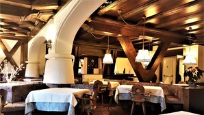 A restaurant with tables covered in white tablecloths, wooden chairs, and hanging pendant lights. - Hotel Sporting (Val di Zoldo)