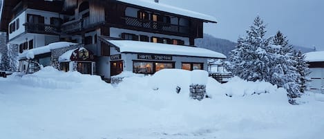Un hotel de varios pisos con tejado cubierto de nieve y un letrero visible de una cafetería.