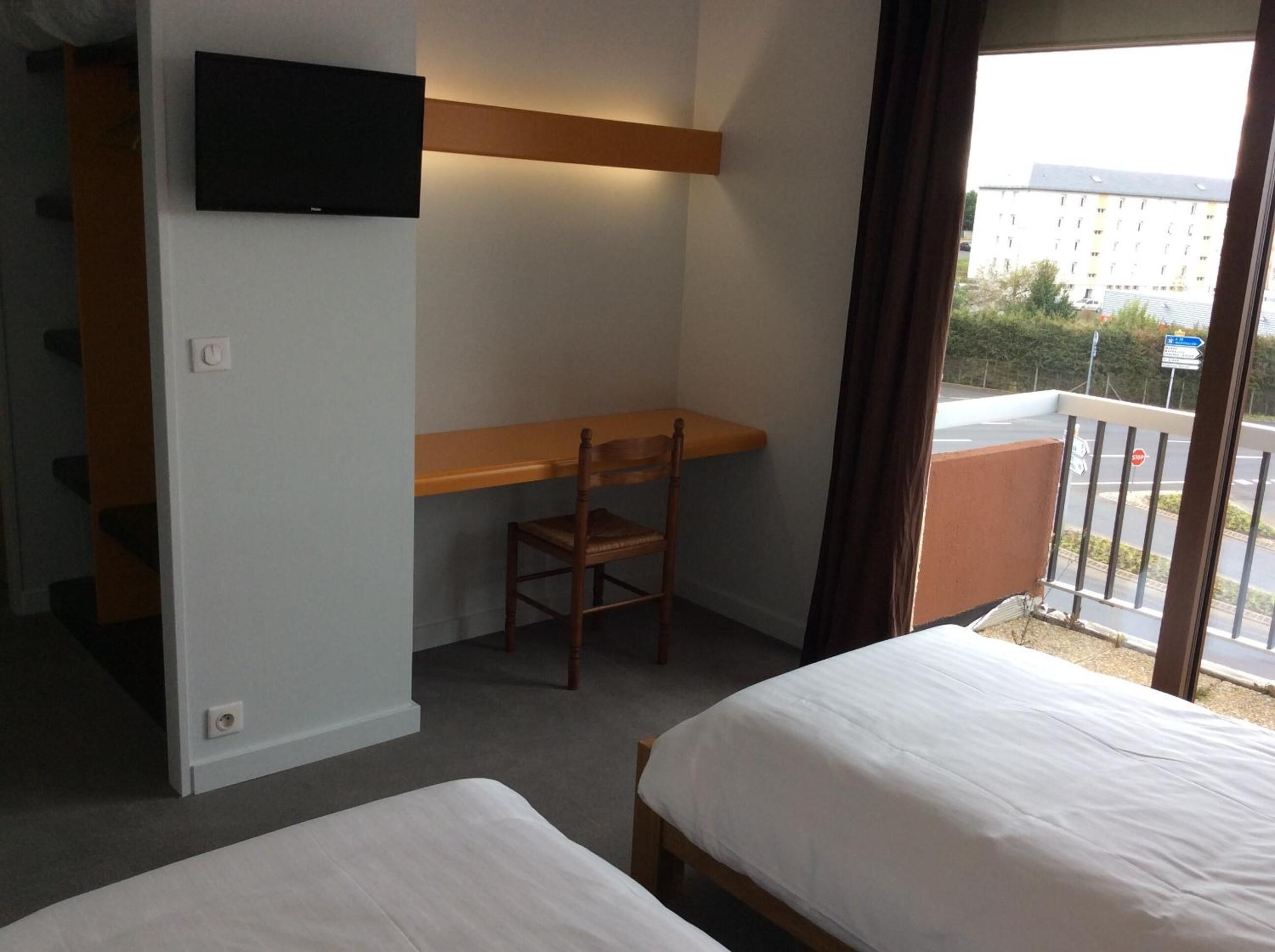 Une chambre d’hôtel équipée d’un bureau, d’une chaise et de deux lits.