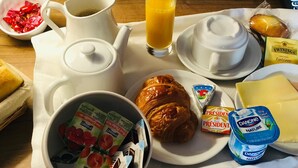 Una bandeja de desayuno con un croissant, yogur, queso, jugo y café.
