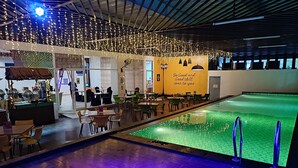 A pool area with a dining section, tables, chairs, and a bar. - Khas Makassar  (Makassar)