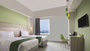 A hotel room with two beds, a desk, a chair, a TV, and a window with a city view. - Khas Makassar  (Makassar)