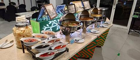 Disposição de buffet com diversos alimentos e utensílios.