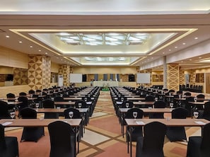 A conference room with rows of tables and chairs, a stage with a podium, and a large screen. - Khas Makassar  (Makassar)