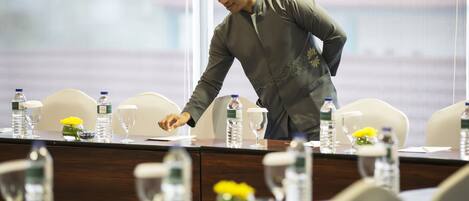 A conference room with a long table, chairs, water bottles, and a vase with yellow flowers.
