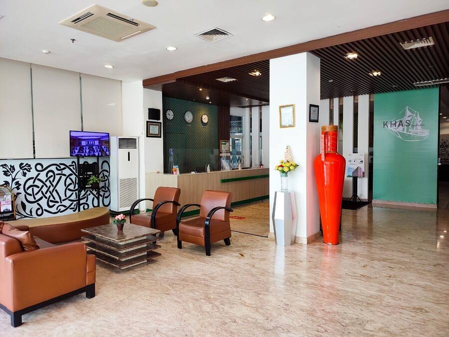A lobby with leather sofas, a reception desk, and a large red vase.
